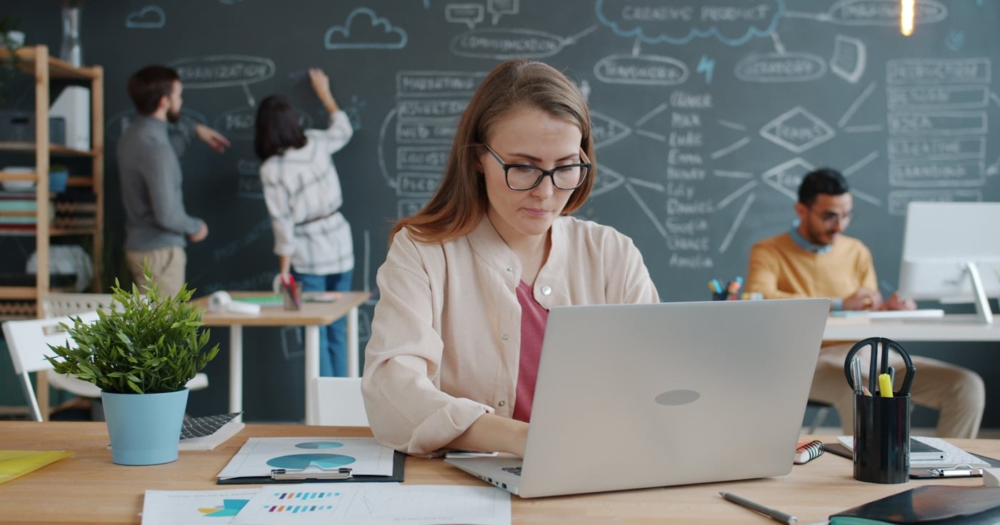 Businesswoman working in modern startup office with team in background